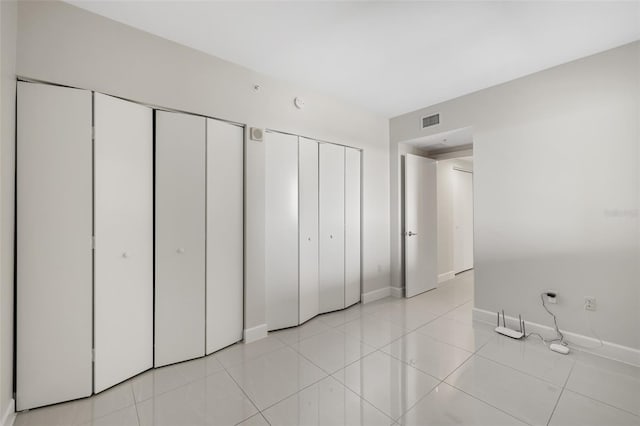 unfurnished bedroom with multiple closets and light tile patterned floors