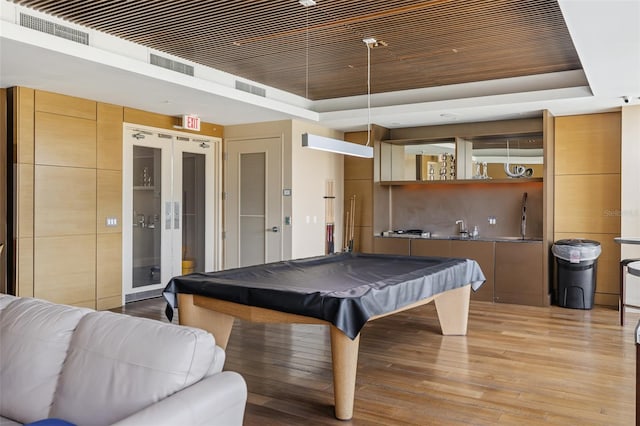 playroom featuring pool table, light hardwood / wood-style floors, and a raised ceiling