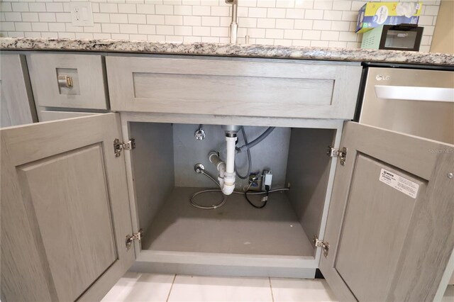 details with light brown cabinetry, light stone counters, backsplash, and light tile patterned floors