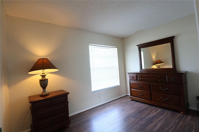 bedroom with a textured ceiling and dark hardwood / wood-style floors