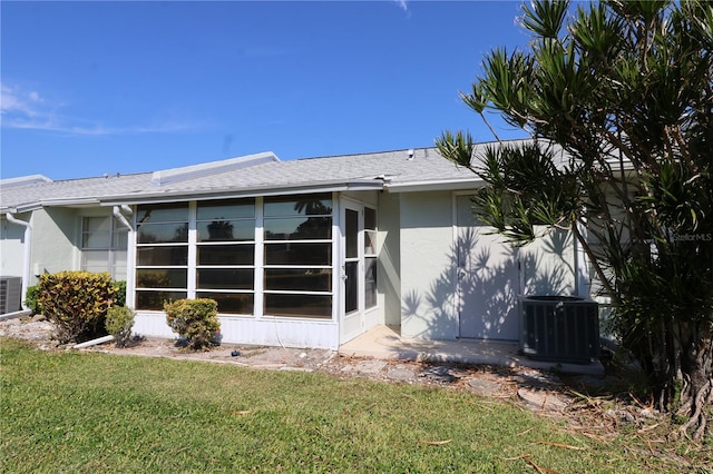 rear view of house featuring a yard, a sunroom, and central air condition unit