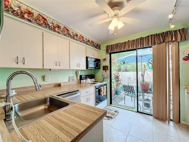 kitchen with white electric range, sink, light tile patterned floors, stainless steel dishwasher, and white cabinetry