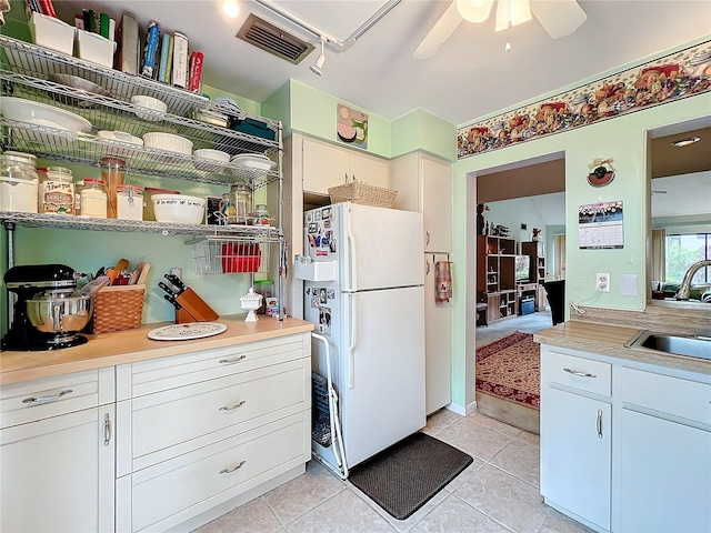 kitchen featuring white cabinetry, white fridge, sink, and light tile patterned floors