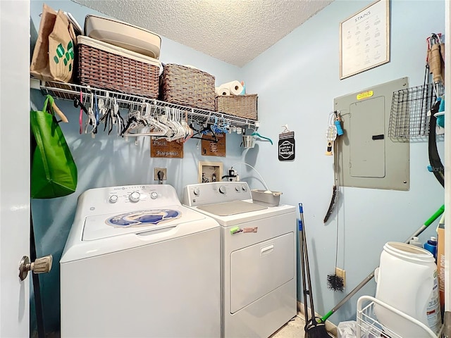 laundry room with electric panel, washer and clothes dryer, and a textured ceiling