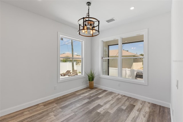 spare room with a notable chandelier and light hardwood / wood-style flooring