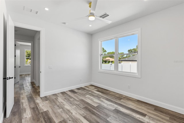 spare room featuring ceiling fan, wood-type flooring, and a wealth of natural light