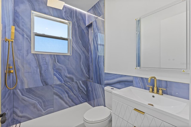 bathroom featuring toilet, vanity, tile walls, and tiled shower