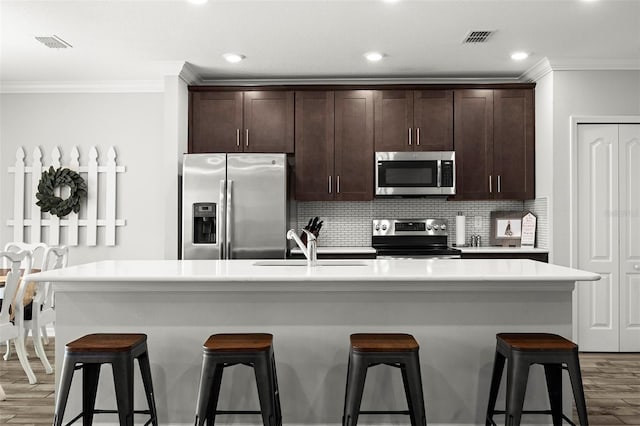 kitchen featuring dark wood-type flooring, stainless steel appliances, and an island with sink