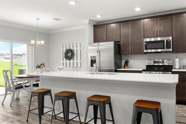 kitchen with a center island with sink, light hardwood / wood-style flooring, a breakfast bar area, and stainless steel appliances