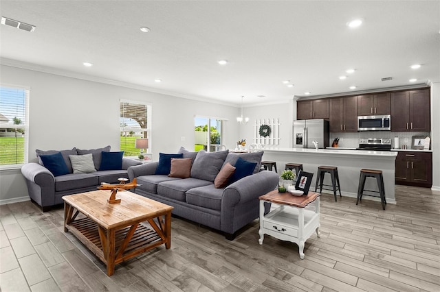 living room featuring ornamental molding, light hardwood / wood-style flooring, and plenty of natural light