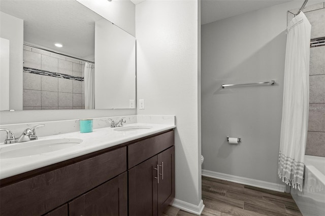 full bathroom with a textured ceiling, hardwood / wood-style floors, toilet, shower / bath combo with shower curtain, and vanity