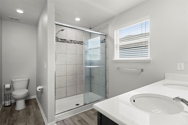 bathroom featuring toilet, vanity, a shower with shower door, and wood-type flooring