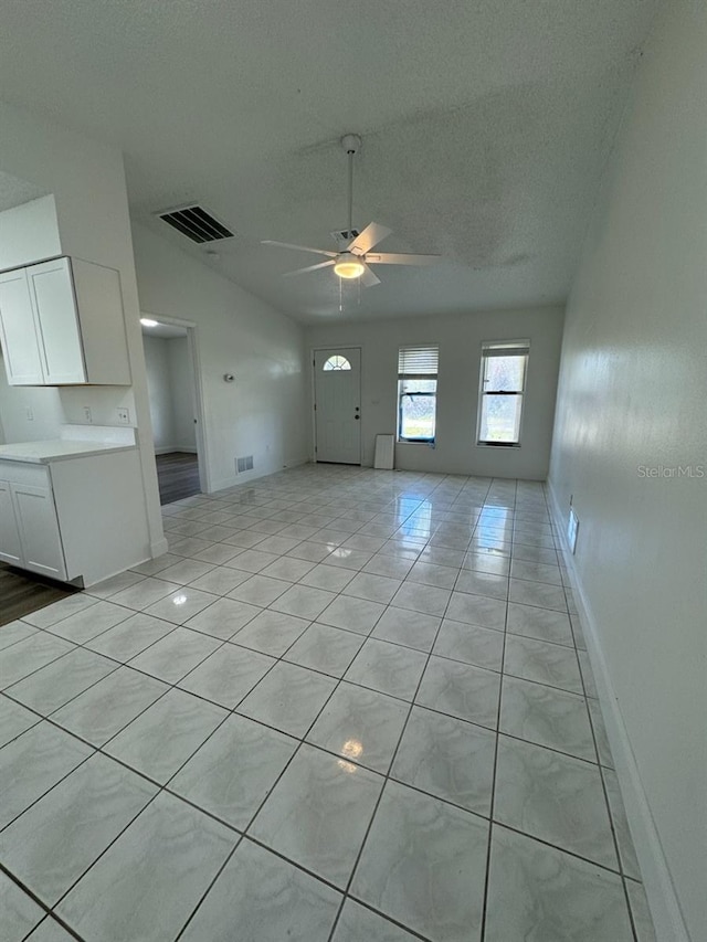 unfurnished living room with a textured ceiling, ceiling fan, and light tile patterned flooring