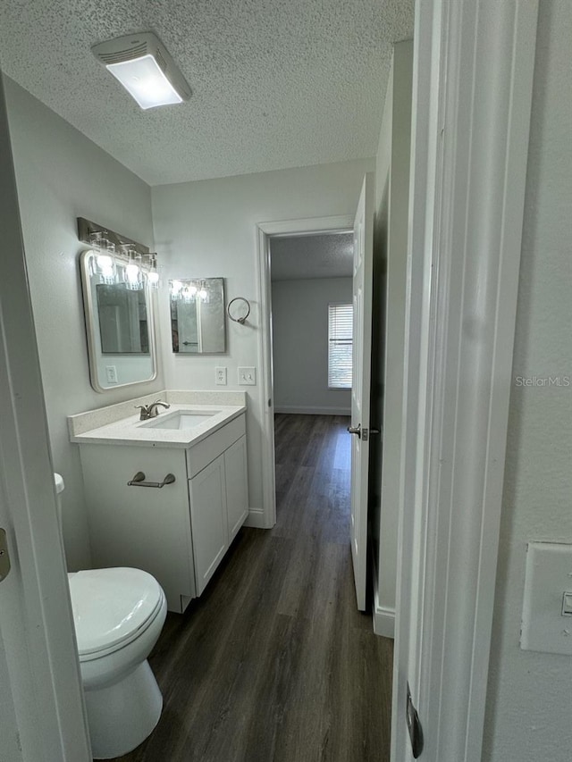 bathroom with wood-type flooring, a textured ceiling, toilet, and vanity