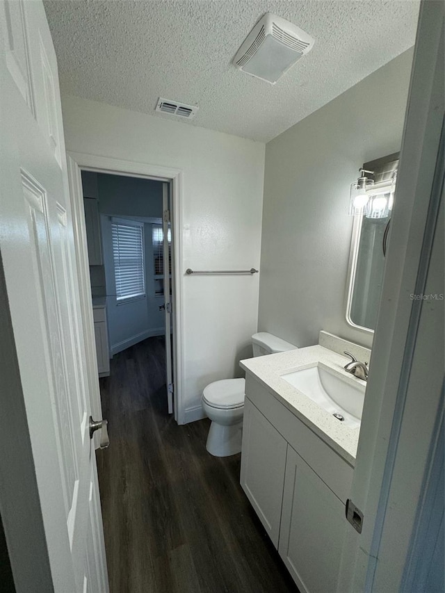 bathroom featuring hardwood / wood-style floors, vanity, a textured ceiling, and toilet