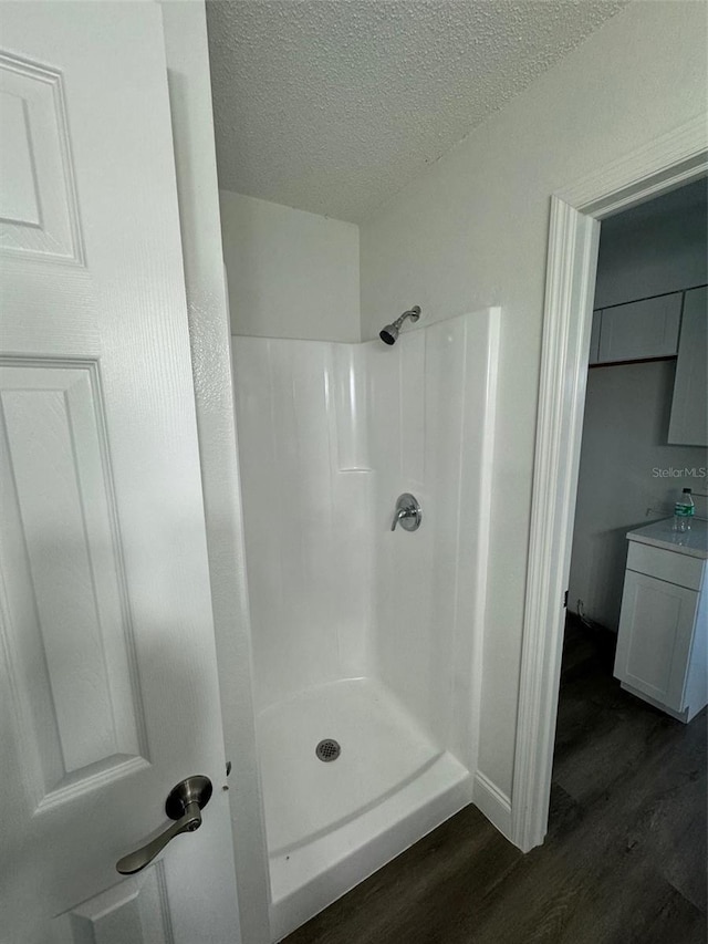 bathroom with walk in shower, hardwood / wood-style floors, vanity, and a textured ceiling