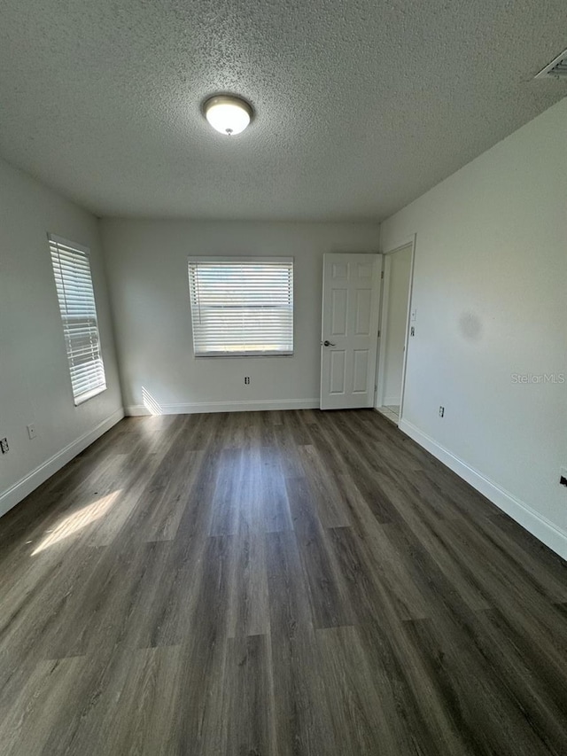 unfurnished room featuring dark hardwood / wood-style floors and a textured ceiling