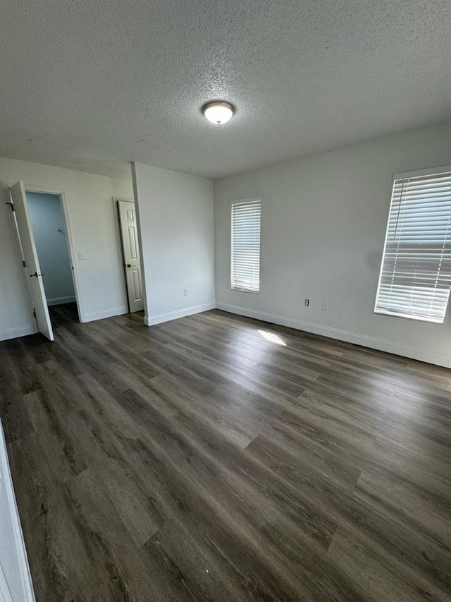 unfurnished room featuring a textured ceiling and dark hardwood / wood-style flooring