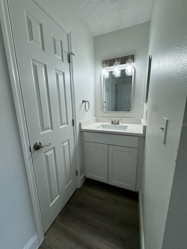 bathroom with hardwood / wood-style floors, vanity, and a textured ceiling