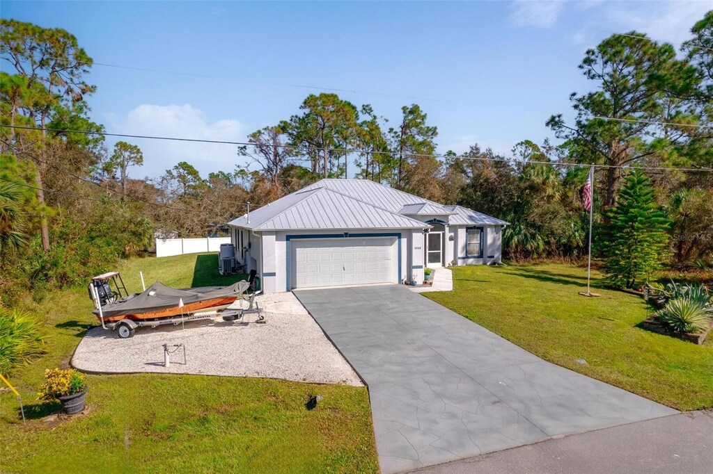 14308 Tugwell Ave, Port Charlotte, FL 33953 - ranch-style home with a standing seam roof, an attached garage, driveway, and a front yard