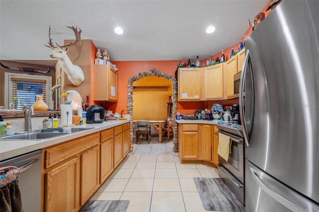 kitchen with light brown cabinetry, sink, appliances with stainless steel finishes, and light tile patterned floors