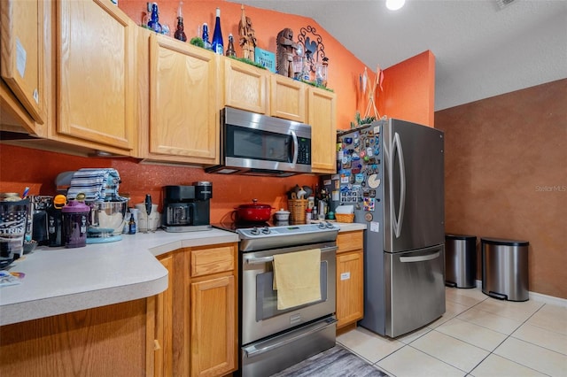 kitchen featuring lofted ceiling, light brown cabinets, stainless steel appliances, and light tile patterned floors