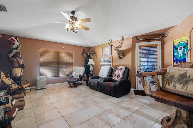 tiled living room featuring lofted ceiling, a textured ceiling, and ceiling fan