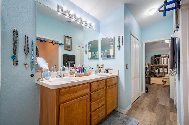 bathroom featuring vanity, lofted ceiling, hardwood / wood-style floors, and a textured ceiling