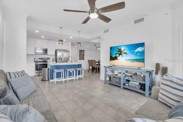 living room featuring ceiling fan, crown molding, sink, and light tile patterned floors