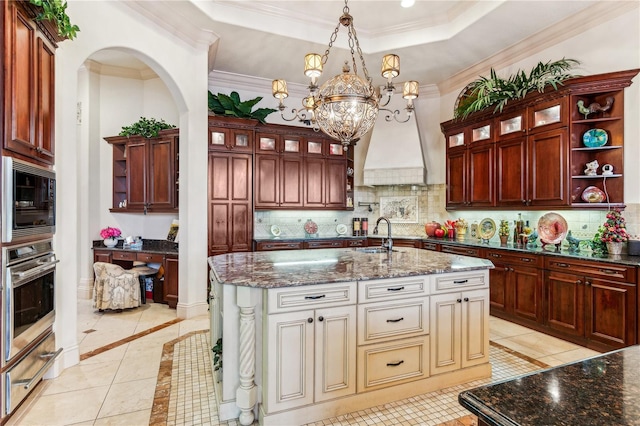 kitchen with built in microwave, stainless steel oven, a tray ceiling, and open shelves