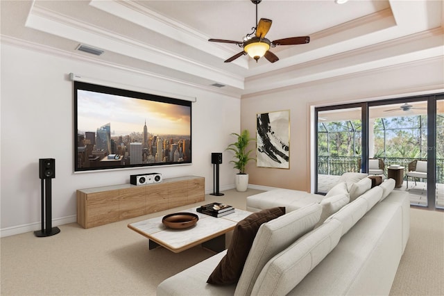 carpeted living room featuring ornamental molding, a raised ceiling, visible vents, and a ceiling fan