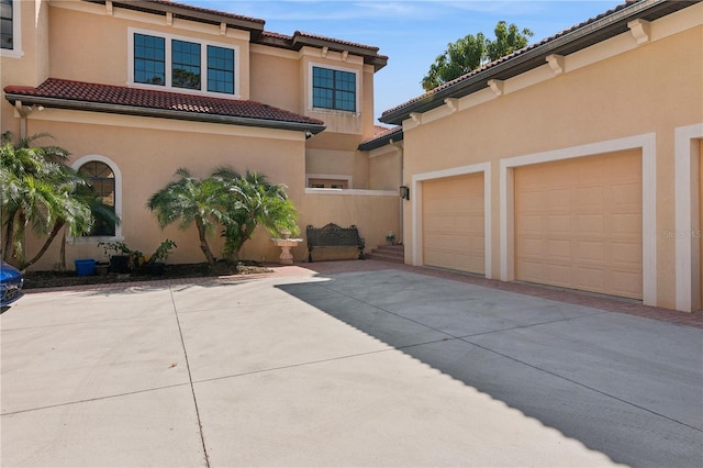 view of front facade featuring a garage, driveway, a tile roof, and stucco siding