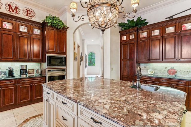 kitchen featuring arched walkways, ornamental molding, built in microwave, stainless steel oven, and a sink