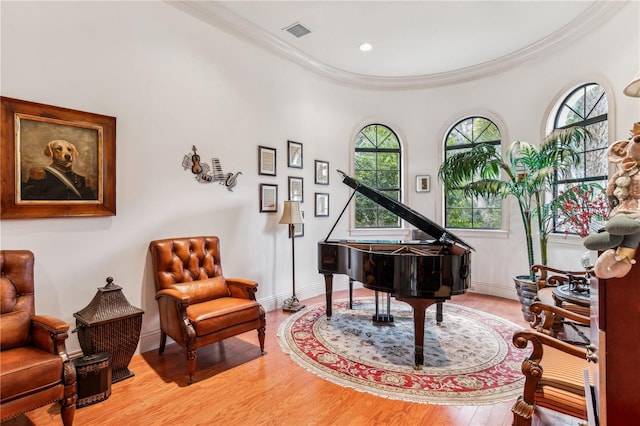 sitting room featuring light wood-style floors, a healthy amount of sunlight, visible vents, and ornamental molding