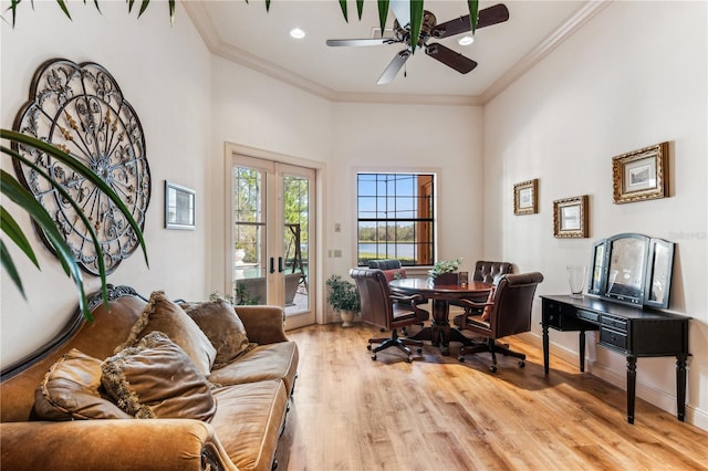 office space with crown molding, light wood finished floors, a towering ceiling, a ceiling fan, and baseboards