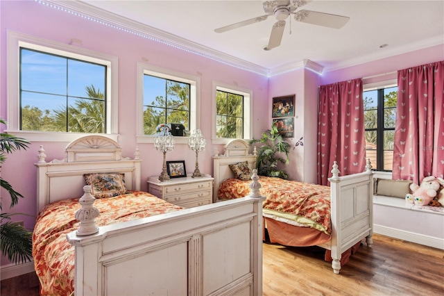 bedroom with light wood-style floors, baseboards, ornamental molding, and a ceiling fan