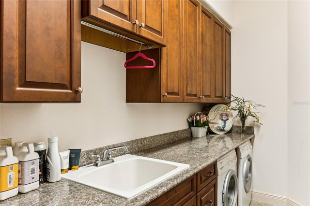 washroom featuring independent washer and dryer, a sink, cabinet space, and baseboards