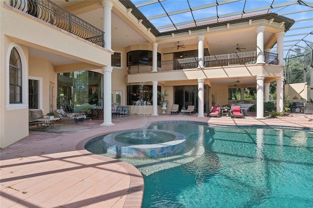 view of pool with a ceiling fan, glass enclosure, a patio area, and a pool with connected hot tub