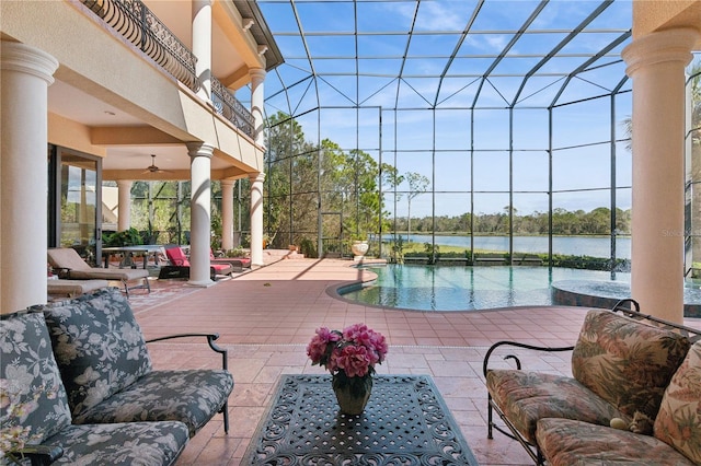 pool with a ceiling fan, a patio, glass enclosure, a water view, and outdoor dining area