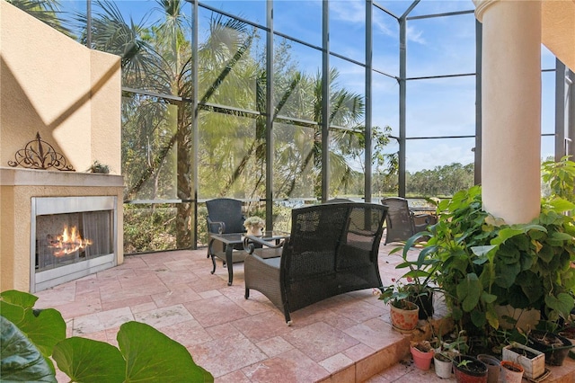 view of patio with glass enclosure and a lit fireplace