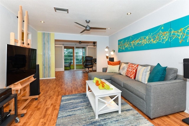 living room with ornamental molding, wood-type flooring, and ceiling fan