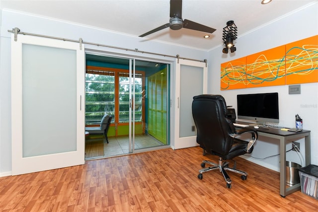 office featuring ceiling fan, ornamental molding, a barn door, and hardwood / wood-style floors