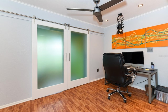 office space with hardwood / wood-style floors, a barn door, crown molding, and ceiling fan