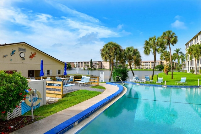 view of pool with a water view and a lawn