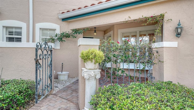 doorway to property with stucco siding and a gate