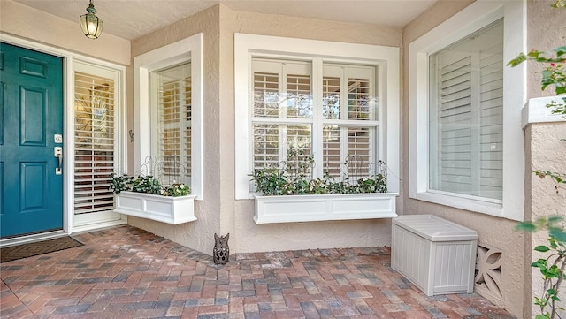 view of exterior entry with covered porch and stucco siding