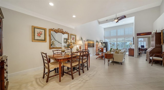 dining area with ceiling fan, crown molding, a towering ceiling, and light tile patterned floors