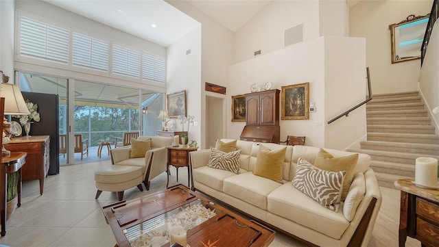 living room featuring visible vents, light tile patterned floors, a high ceiling, and stairway