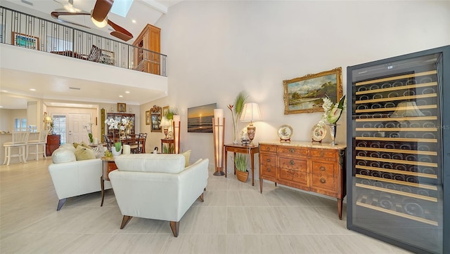 living room featuring beverage cooler, ceiling fan, light tile patterned floors, high vaulted ceiling, and a skylight