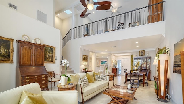 tiled living room with a towering ceiling, ornamental molding, a skylight, and ceiling fan